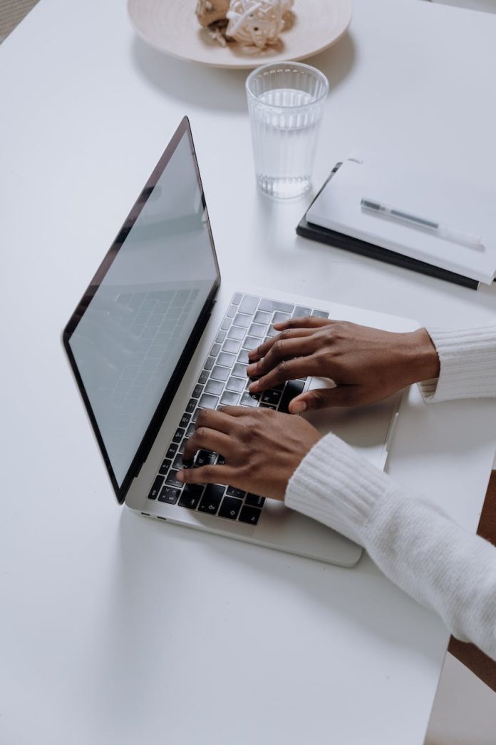 pexels-photo-5076520 person in white long sleeve shirt using macbook pro