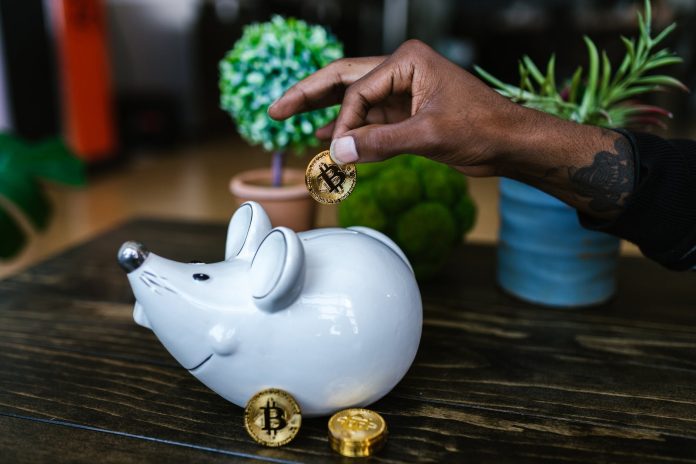 pexels-photo-8370757 a person putting bitcoin in a piggy bank